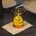 A Sterno Petite Amber Votive Glass with a lit candle on a table.