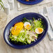 An Acopa Capri deep sea cobalt oval stoneware coupe platter with a salad, hard boiled eggs, and avocado.