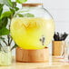 An Acopa glass fishbowl beverage dispenser with lemonade and lemons.