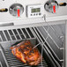 A piece of meat being cooked on a grill with a Taylor digital thermometer.