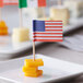 A plate of cheese with Choice American flag toothpicks in it.