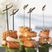 Bamboo skewers with salmon, cucumber, and celery on a table.