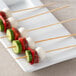 A group of EcoChoice bamboo skewers with meat and vegetables on a white plate.