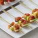 A plate of Bamboo by EcoChoice green bamboo paddle skewers with vegetables and meat on a table.