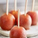 A close-up of a group of apples on round wooden sticks.