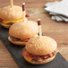 Three hamburgers on a slate with Bamboo by EcoChoice trident skewers in them.