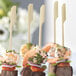 Bamboo skewers with shrimp appetizers on a white plate.