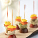 A tray of assorted food on EcoChoice red bamboo skewers.