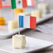 A plate of cheese with Choice French flag food picks in it.