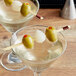 A martini glass with olives and onions on a Bamboo by EcoChoice skewer.