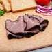 Sliced Mrs. Ressler's roast beef on a cutting board with bread.
