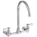 A silver Regency wall mount faucet with 8 1/2" swivel gooseneck spout and two red knobs.