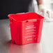 A red San Jamar sanitizing pail on a counter.