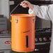 A person holding a large orange Fryclone utility pail.