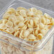 A clear container filled with Barilla Orecchiette pasta on a table.