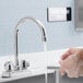 A person using a Regency gooseneck faucet nozzle to wash their hands.