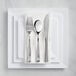 A Visions white plastic plate with silver classic flatware on a napkin.