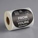 A roll of TamperSafe round black paper labels with the words "From Our Kitchen To Yours" on a counter.