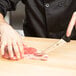 A person using a Victorinox 6" Semi-Stiff Narrow Boning Knife to cut meat on a cutting board.