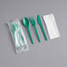 A green EcoChoice plastic fork, spoon, and knife wrapped in a white napkin.