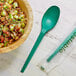 A bowl of food with a green EcoChoice CPLA spoon next to it.