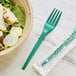 A bowl of salad with a green EcoChoice CPLA fork next to it.