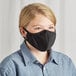 A woman wearing a black Mercer Culinary reusable face mask.