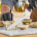 A person using a Schraf serrated bread knife to cut a piece of bread.