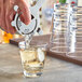 A hand pouring liquid into an Acopa Endure Tritan plastic rocks glass with ice.