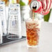 A hand pouring a can of soda into an Acopa Endure Tritan highball glass of ice.