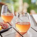Two Acopa Endure stemless wine glasses of wine and food on an outdoor table.
