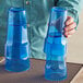 A person holding two blue Choice plastic tumblers.