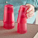 A woman holding a pair of red Choice plastic tumblers.