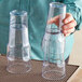 A person holding a pair of Choice clear plastic paneled tumblers.
