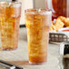 Two Choice clear plastic tumblers filled with iced tea on a table.