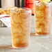 Two Choice clear plastic pebbled tumblers filled with iced tea on a table.