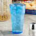 A blue plastic Choice paneled tumbler with ice and a straw.