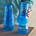 A person holding a pair of blue plastic cups.