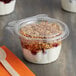A Dart plastic container with a white lid filled with granola and yogurt.