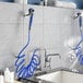 A Waterloo pet grooming faucet with blue and white hoses and a shower head.