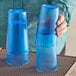 A person holding a pair of Choice blue plastic tumblers.
