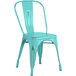 A seafoam metal chair with a metal back.