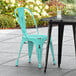 A Lancaster Table & Seating distressed seafoam outdoor cafe chair sits at a table.