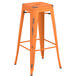 A Lancaster Table & Seating distressed orange metal backless barstool with a black seat.