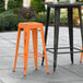 A black and orange Lancaster Table & Seating outdoor barstool on a patio.