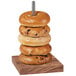 A stack of bagels on a wooden and chrome display pole.