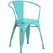 A Lancaster Table & Seating distressed seafoam metal arm chair with a metal back.