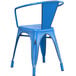 A Lancaster Table & Seating distressed blue metal outdoor arm chair on a patio.