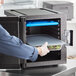A person using a CaterGator Dash front loading food pan carrier to store food in a refrigerator.