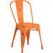 A Lancaster Table & Seating distressed orange metal chair.